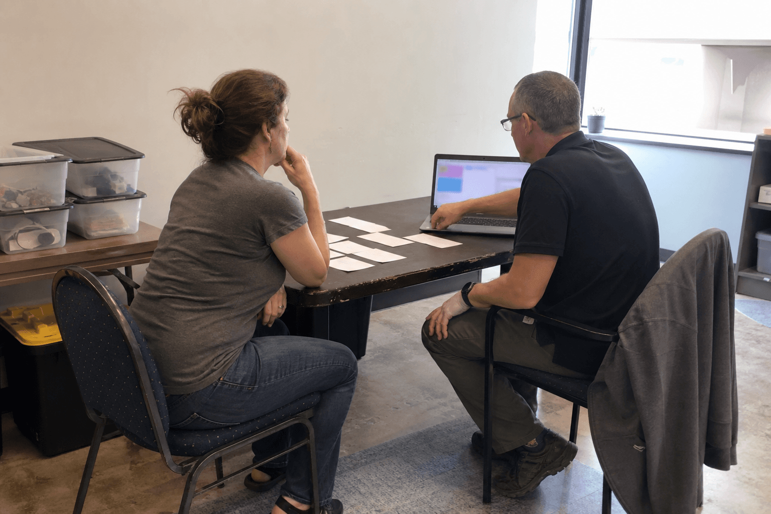 Service business operators reviewing blank workflow cards beside an abstract screen in a practical office