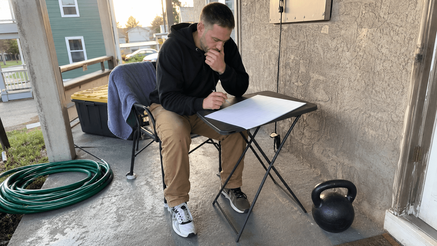 Adults reviewing a blank clipboard beside kettlebells in a lived-in garage