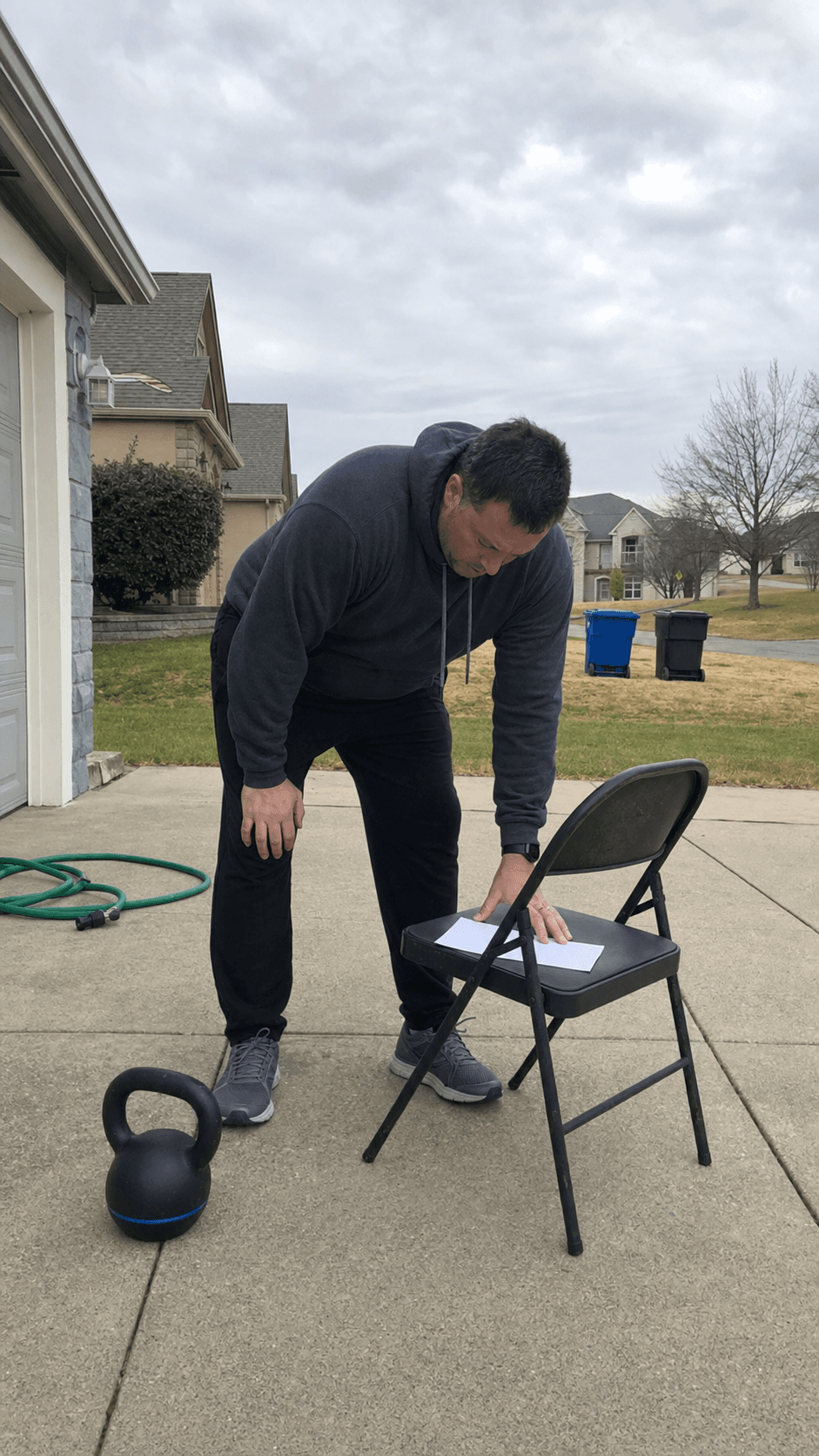 Adult reviewing a blank driveway training check-in beside a kettlebell